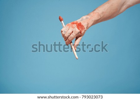 hand with a brush on a blue background, art                               