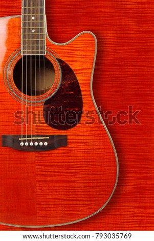 Musical instrument - Silhouette of a orange flame maple tiger maple acoustic guitar with cutaway on a flame maple background.