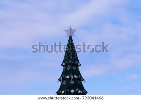the top of the artificial Christmas tree at the background of the evening sky