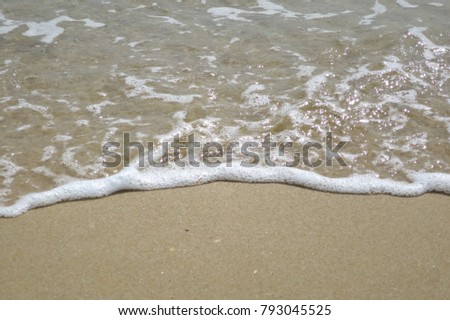 The waves beat at the beach with sand and shell fragments. Nature background concept.

