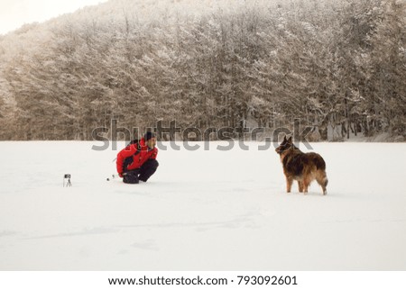 hiker playing with his dog in the snow, europe forest