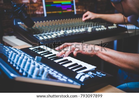 male musician playing midi keyboard synthesizer in recording studio, focus on hands Royalty-Free Stock Photo #793097899