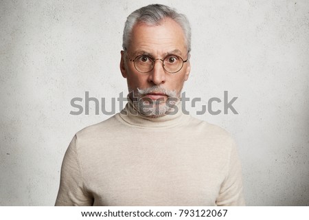 Horiontal shot of bearded mature man looks with stupefied shocked expression at camera, can`t imagine what he hears, dressed casually, isolated over white background. Surprised elderly person Royalty-Free Stock Photo #793122067