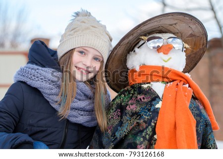 Happy young girl with a snowman, close up. Ukraine