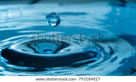 water drop splash in a glass blue colored Royalty-Free Stock Photo #793184827
