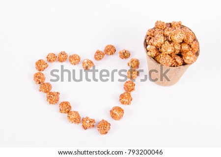 Caramel popcorn in a paper bucket and a heart made of popcorn. Romantic concept. copy space