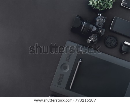 top view of graphic design work station, work space concept with digital camera, memory card, graphic tablet on black background with copy space