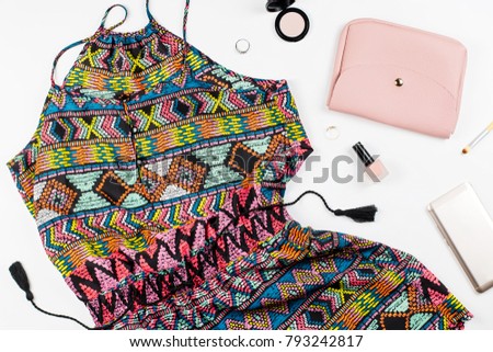 Colorful playsuit, smartphone, make up products and accessories on white background.