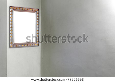 A blank picture frame hanging at the corner of a blank empty cement wall.