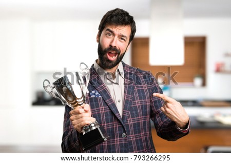 Happy Well dressed man holding a trophy inside house
