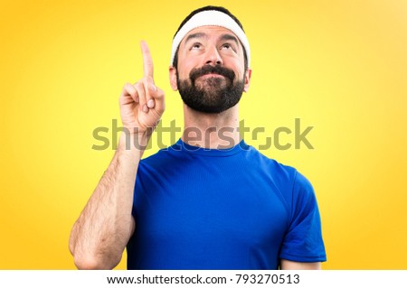Funny sportsman pointing up on colorful background