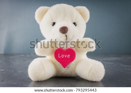 White toy teddy bear with heart on a gray background. The symbol of the day of lovers. Valentine's Day. Concept February 14