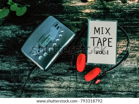 Mixtape and cassette player with red vintage earphones on wood background