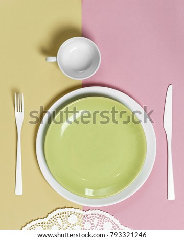 Light green plate and white cutlery on a pink-green background. Colors in the style of pop art.
