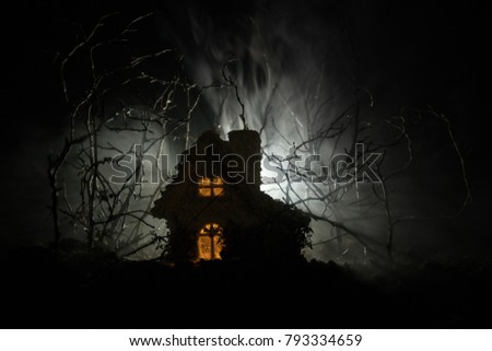 Old house with a Ghost in the forest at night or Abandoned Haunted Horror House in fog. Old mystic building in dead tree forest. Horror Halloween concept.