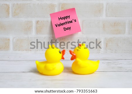 Valentine's day theme. Selective focus of pink sticky notes written with 'HAPPY VALENTINE'S DAY' with a couple yellow duck chatting.