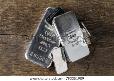 Silver bullion on wood texture background. Coins and bars.