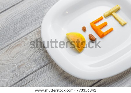 fruit on a plate of a word diet of apple, kiwi, carrots, nuts and raisins. weight control for a healthy body concept