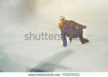 Unidentified rescue extreme kid child  on rink.  Ice Skaters skating on a public child e rink , wearing  yellow  helmet and uniform . Concept of learning    skating. 