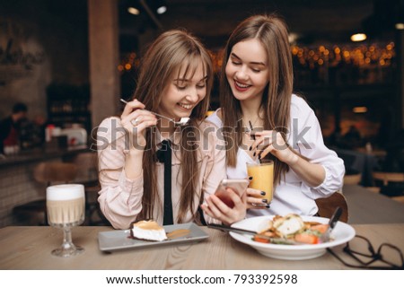 Two girls having lunch in a cafe with phone
