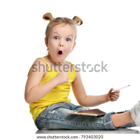 Young girl kid sitting surprised with digital tablet touch screen pad with pencil  in yellow shirt isolated on a white background