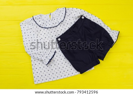 Set of sleeping garments on yellow wooden background. White pajama top and navy shorts. Anchor and handwheel pattern.