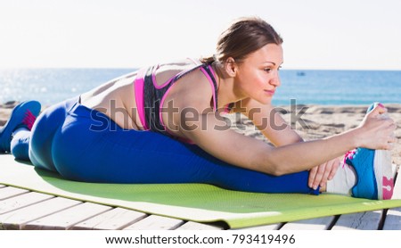Woman 28-35 years old is stretching on the beach near sea.  Royalty-Free Stock Photo #793419496