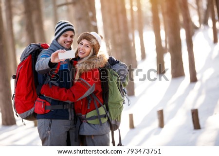 Boy and girl taking photo while hiking in snowy nature