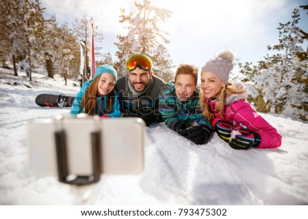 Happy family enjoying winter vacations in mountains and making selfie