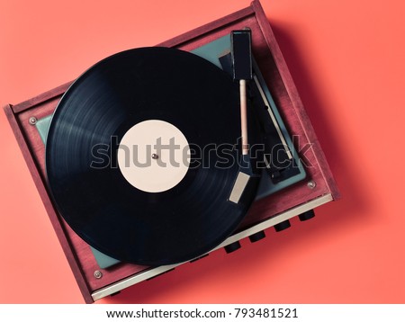 Vintage vinyl turntable with vinyl plate on an orange background. Entertainment 70s. Listen to music. Top view. Royalty-Free Stock Photo #793481521