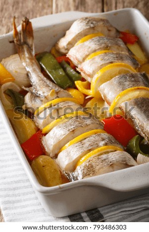 Dietary food pink cod baked with vegetables and lemon in a baking dish close-up on the table. vertical
