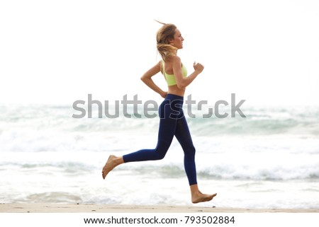 Side portrait of young sport woman running by water ion beach