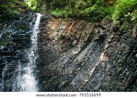 Picturesque waterfall in forest. Landscape with stream of water on rock in virgin nature. Untouched corner of earth