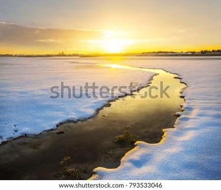 small melted river among a snowbound coast at the sunset