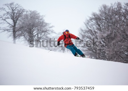 A skier is riding downhill in the deep snow. Winter season, good powder day.