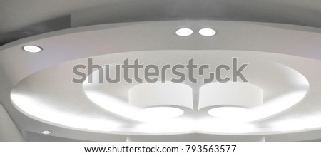 Photo of white hi-tech ceiling with lighting fixtures / spot lamps. Fragment of minimalist modern architecture. Abstract contemporary interior design.