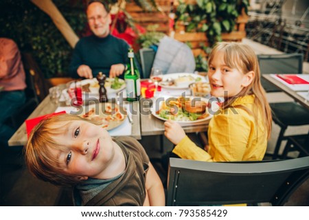 Happy family eating hamburger with french fries and pizza in outdoor restaurant Royalty-Free Stock Photo #793585429