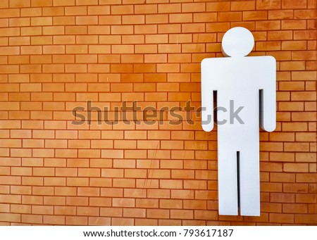 Male toilet symbol on Brick wall. Copy space on lefthand side. Background texture.