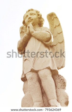 Sculpture of angel in the cemetery park. Stone statue of angel praying.