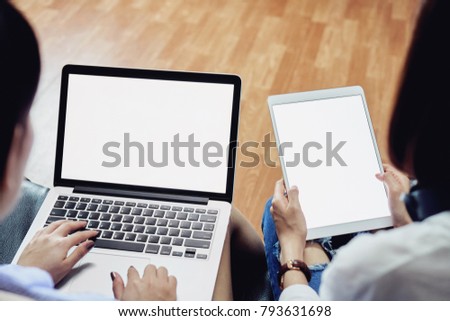 Woman sitting on black sofa using computer and blank screen tablet. Blank screen for the graphics. Concepts for Digital Technology in Everyday Life.               