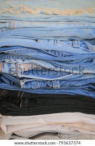 Stack of blue jeans on wooden background with copy space