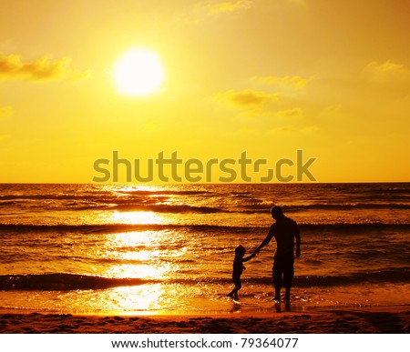 child with his father at sea. Sunset