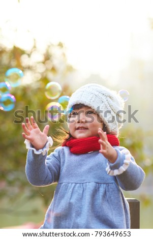 lovely little asian girl playing with soap bubble outdoor in the