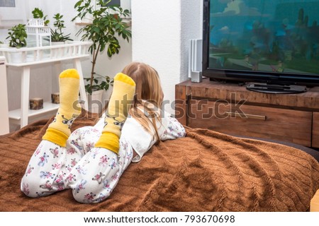 Little girl watching television on the sofa at home