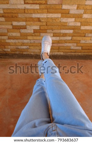 Old White Shoes. Woman Wear White Sneaker and Blue Jeans on Orange Brick Wall Background Great for Any Use.
