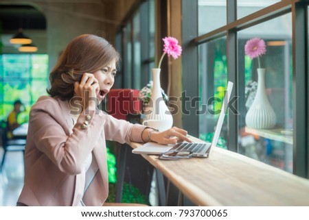 Young asian business woman talking on the cellphone with stressed face or be unhappy with the result of something on the laptop. Royalty-Free Stock Photo #793700065