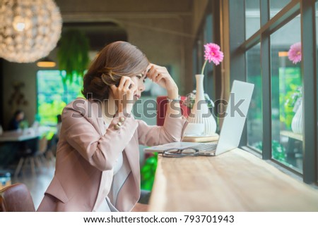 Young asian business woman talking on the cellphone with stressed face or be unhappy with the result of something on the laptop. Royalty-Free Stock Photo #793701943