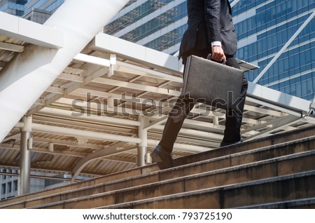 young handsome business man holding briefcase and walking up the stairs going to work time at morning in the city, determination, confidence, lifestyle, rush hour, grow up and successful concept Royalty-Free Stock Photo #793725190