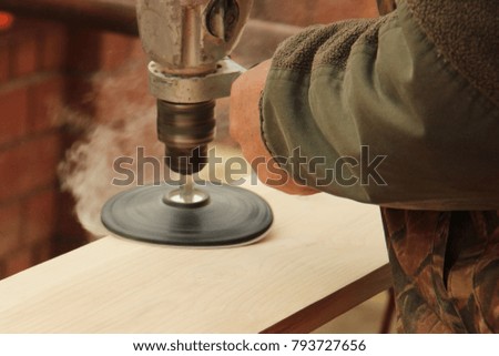 Process with angle grinder. Grinding of a wooden board 20 mm for the manufacture of furniture and shelves. An old man is working in the open air. Carpentry as a hobby. grinding wheel in daddy hand.