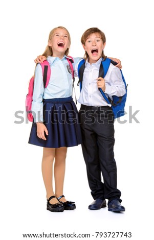 School fashion. Two cheerful children in school uniform and with school backpacks posing at studio. Isolated over white background. Copy space. Full length portrait.